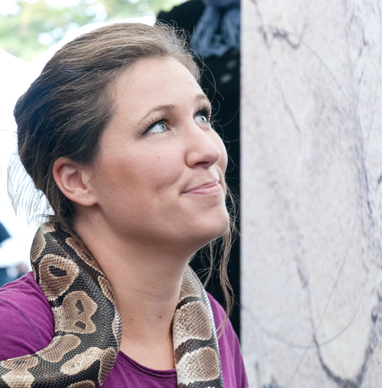 En person med en orm runt halsen tittar på någonting utanför bild uppe till höger.