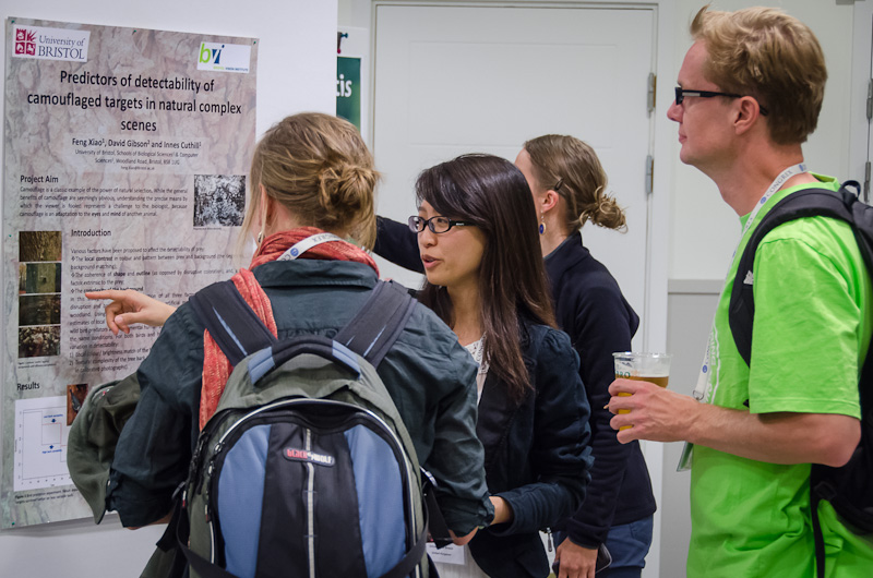 Tre personer står och pekar och tittar på en poster.