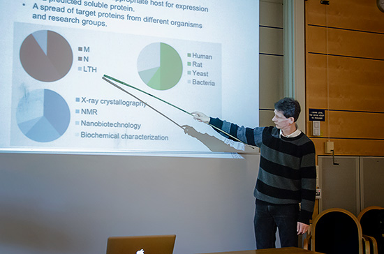 En person står och pekar med en pekpinne på en projektorduk med tårtdiagram.