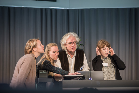 Four people are gathered around a computer.