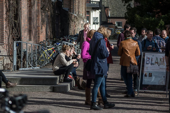 A lot of people are mingling outside in the sun.