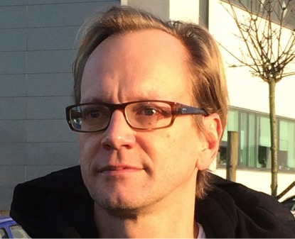 Portrait of a person standing outside with a building in the background.