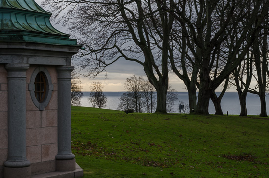 Havet syns i bakgrunden, några träd i mellangrunden och en del av en byggnad i förgrunden.