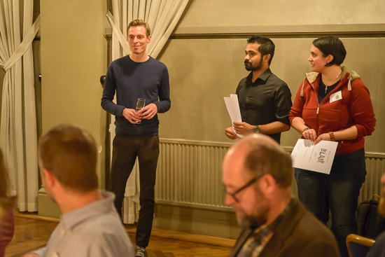 Three people are standing with papers in their hands.