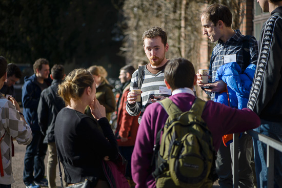 A lot of people are standing outside drinking coffee.