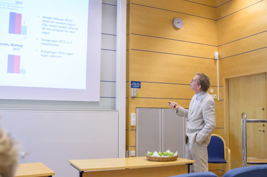 A person is giving a talk and points at a big screen.