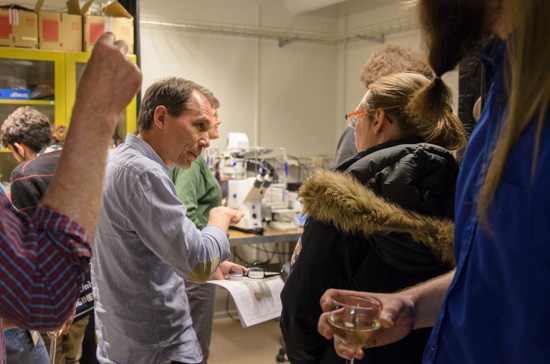 A person explains things to other people in a crowded lab.