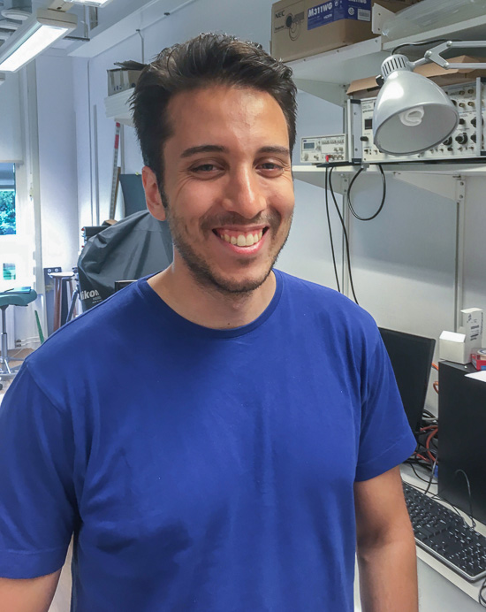 A smiling person is standing in the lab.