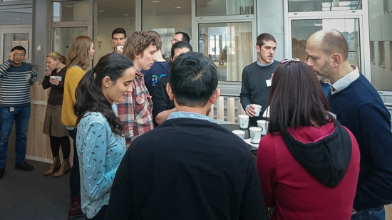 Some people are standing drinking coffee and talking.