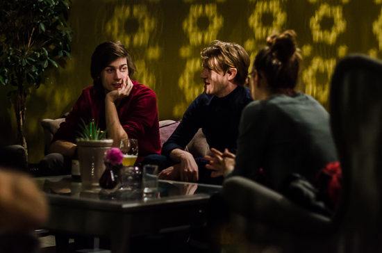 Three people are sitting talking in a dark room with a lot of shadows.