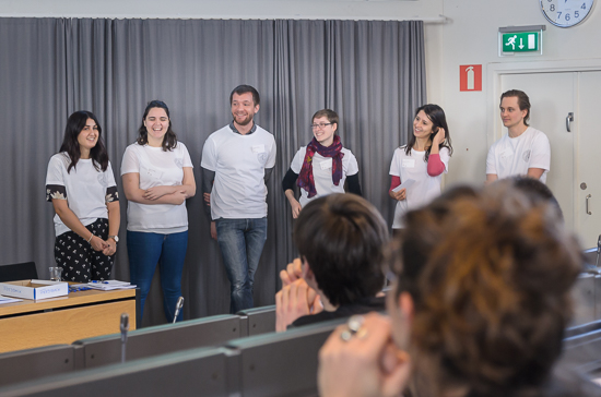 A group are people are standing in a lecture hall. Photo.
