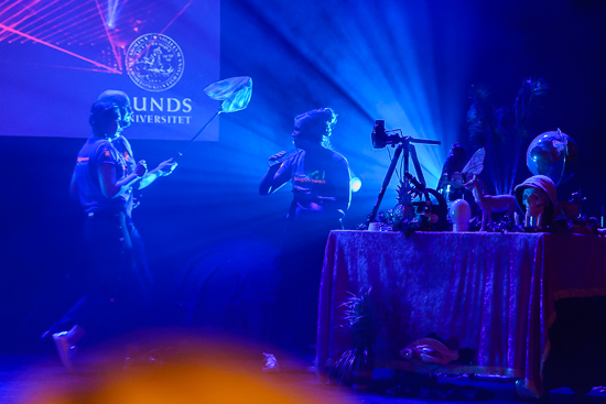 Persons standing on a scene in blue light.