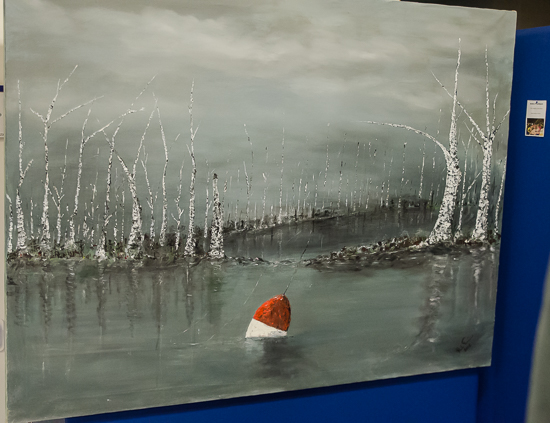 En målning av trädstammar runt en sjö med en boj i. Foto.