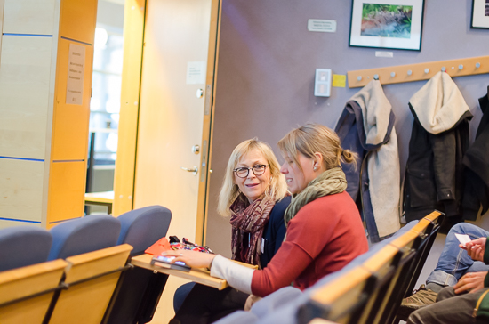 Two persons are sitting talking in a lecture hall.