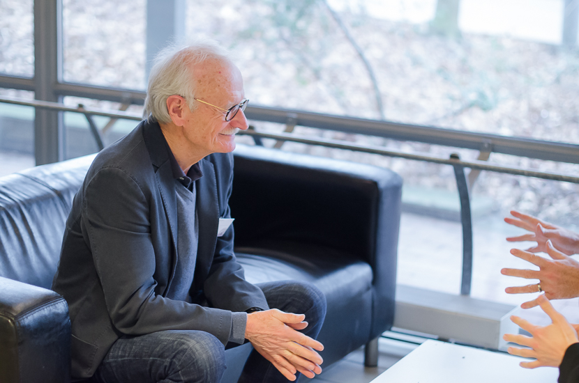 A person is sitting looking at two pair of hands gesticulating.