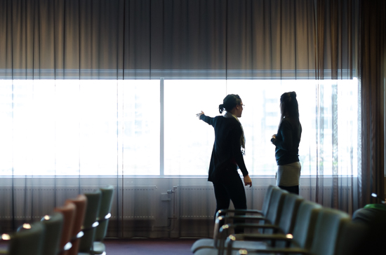 Two persons are standing in siluette against a window talking.