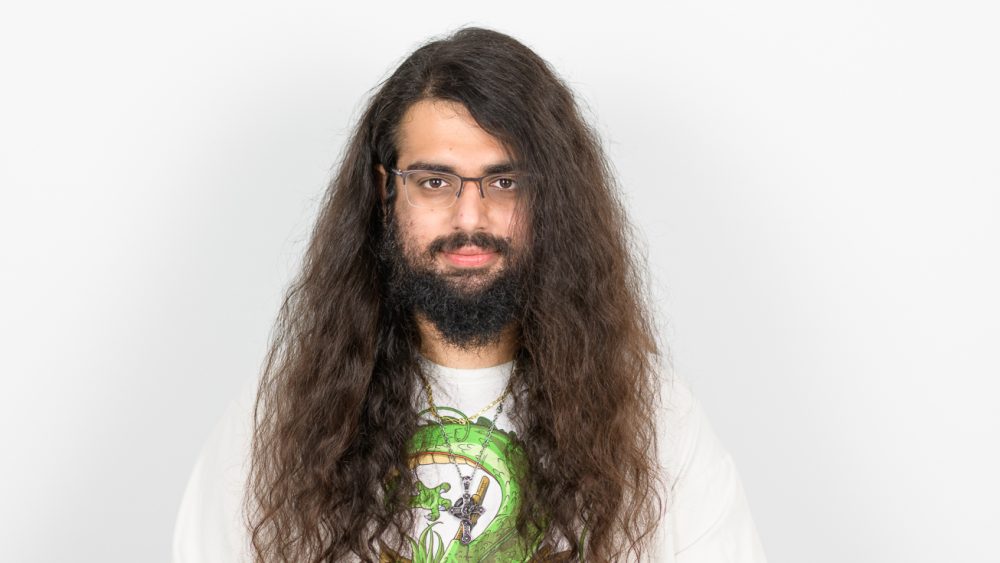 Porträttbild på NIma MOhseni, långt hår, glasögon och skägg. Foto.