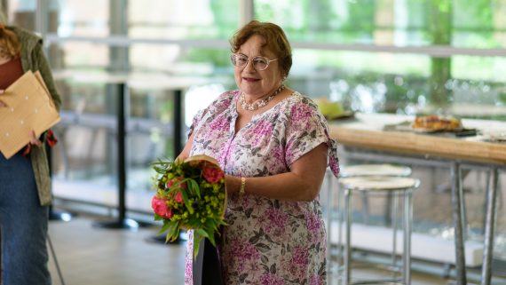 En person står och håller en blombukett. Foto.