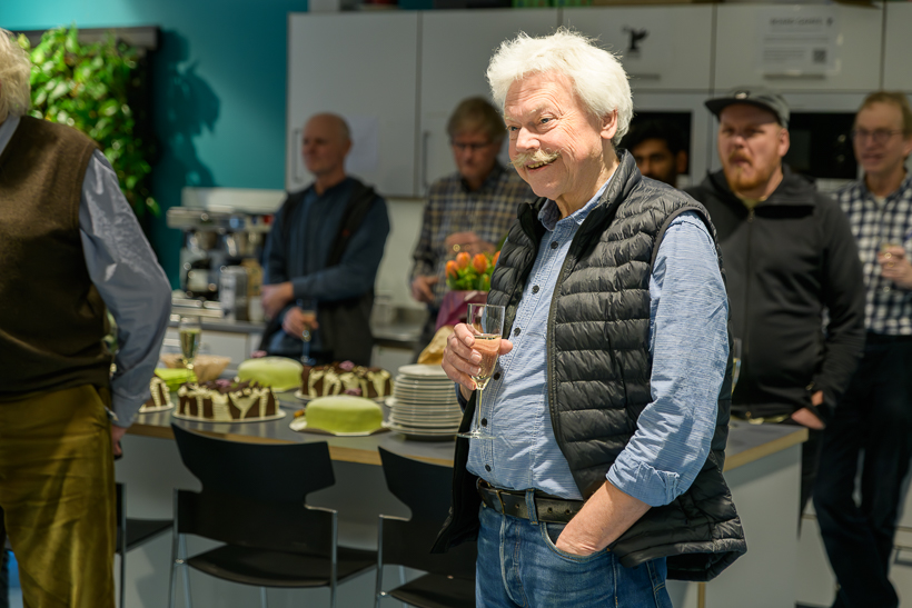 En person står med ett glas i handen och pratar. Foto.