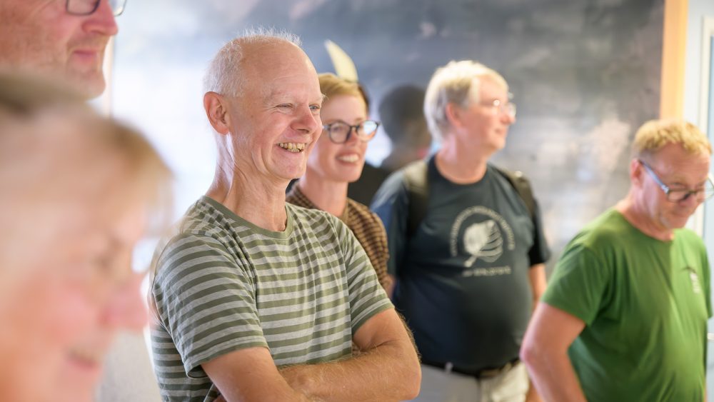 En person står och ler. Foto.