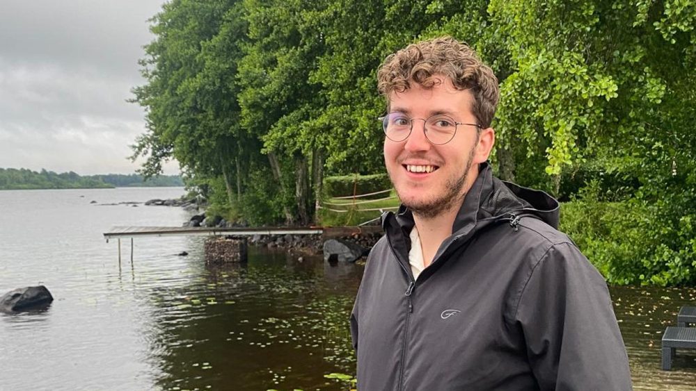 A person is standing in front of a lake. Photo.