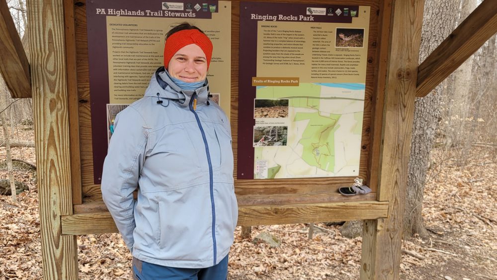 A person is standing in front of an information board outside. Photo.